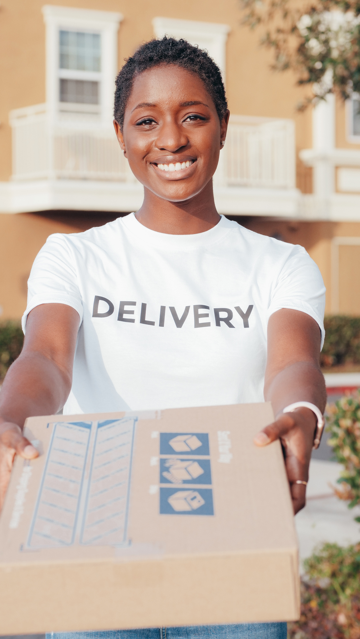 Smiling Female Courier Holding a Package Outdoors